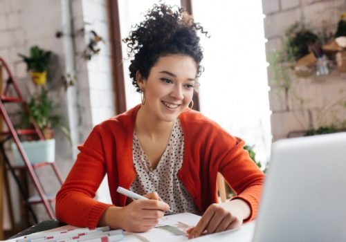young-smilng-woman-with-dark-curly-hair-sitting-table-happily-working-laptop-drawing-fashion-illustr.jpeg